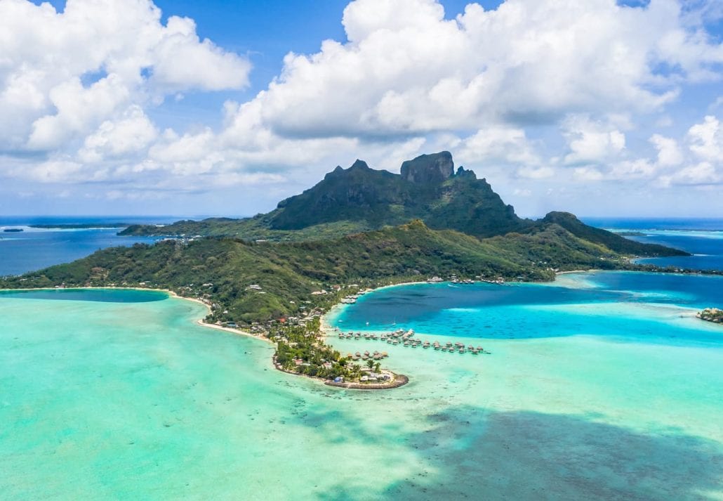 Aerial view of Matira point with overwater bungalows of a luxury resorts and Mount Otemanu with amazing divine coast and lagoon.