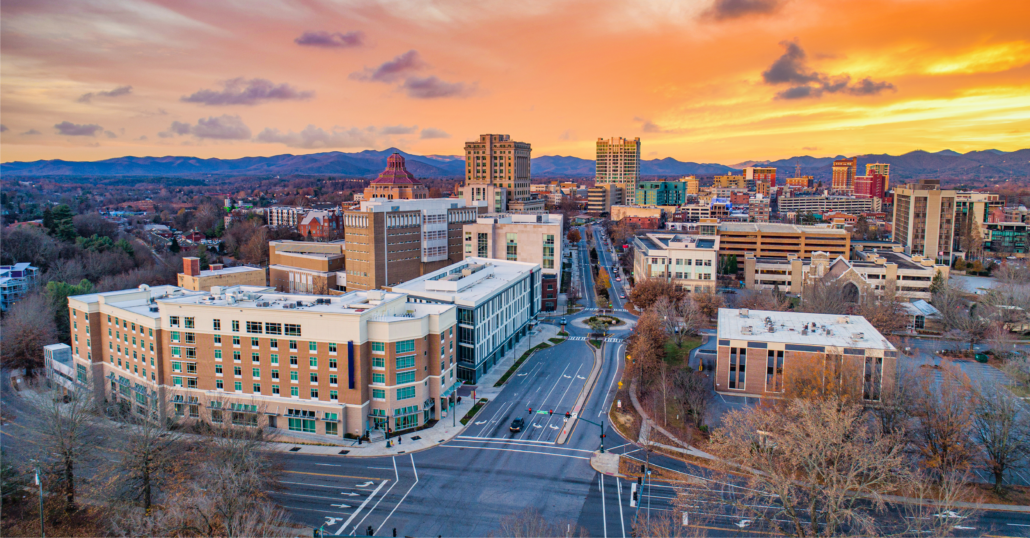 
Aerial view of the buildings at Downtown Asheville surrounded by the Appalachian Mountains during a the sunset.
