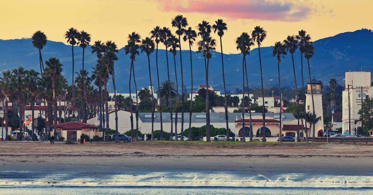 View of the Santa Barbara coastline with mountains and palm trees during sunset.