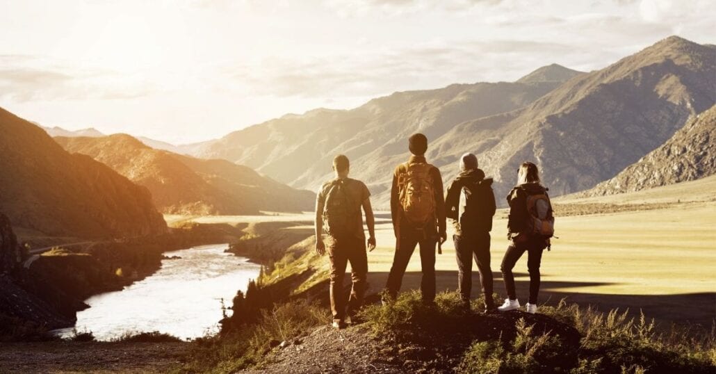 A group of four friends contemplating a mountainous National Park after hiking, at dawn.