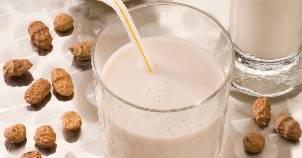 A glass of Horchata de Chufa surrounded by tigernuts.