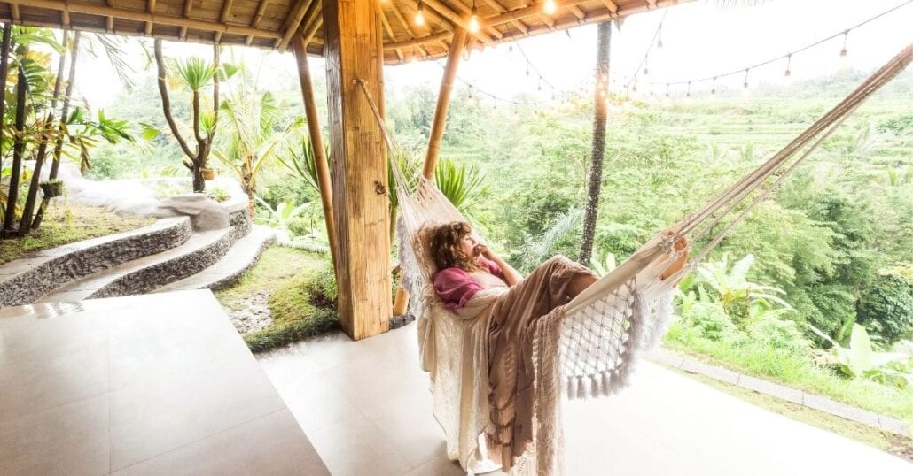 A woman lying in a hammock at a hotel  surrounded by nature, in Bali.