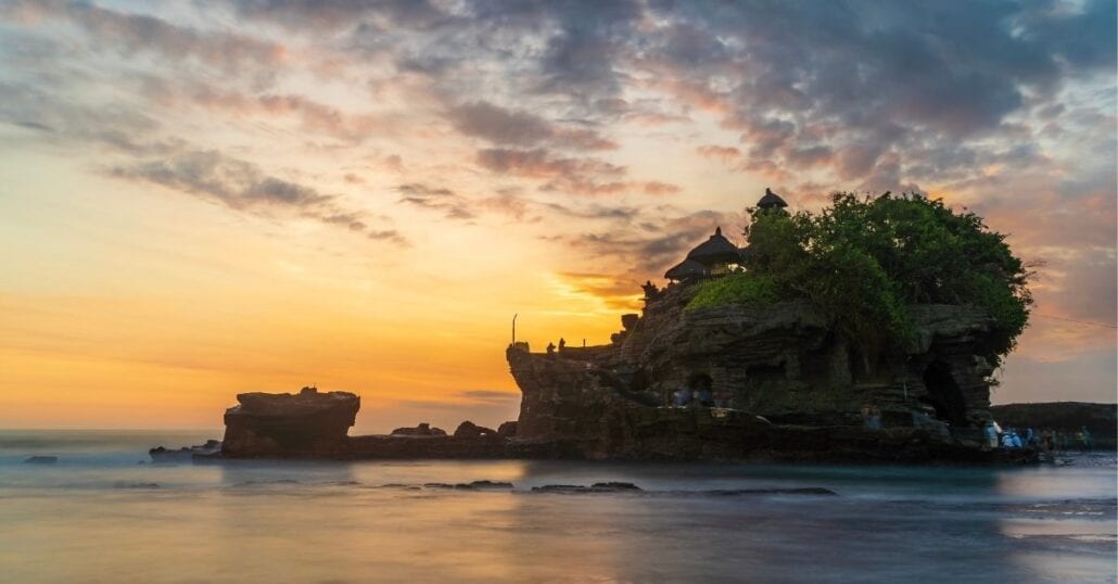 View of the Tanah Lot Temple, in Bali, during an orange sunset.