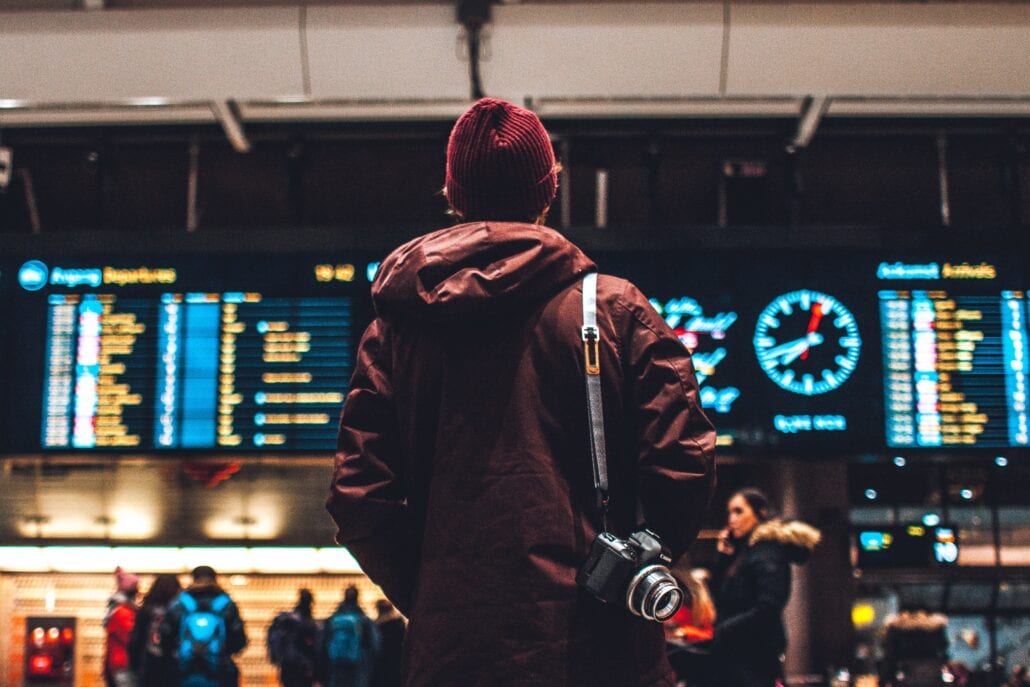 Young traveler checking the timetable at an airport at night.