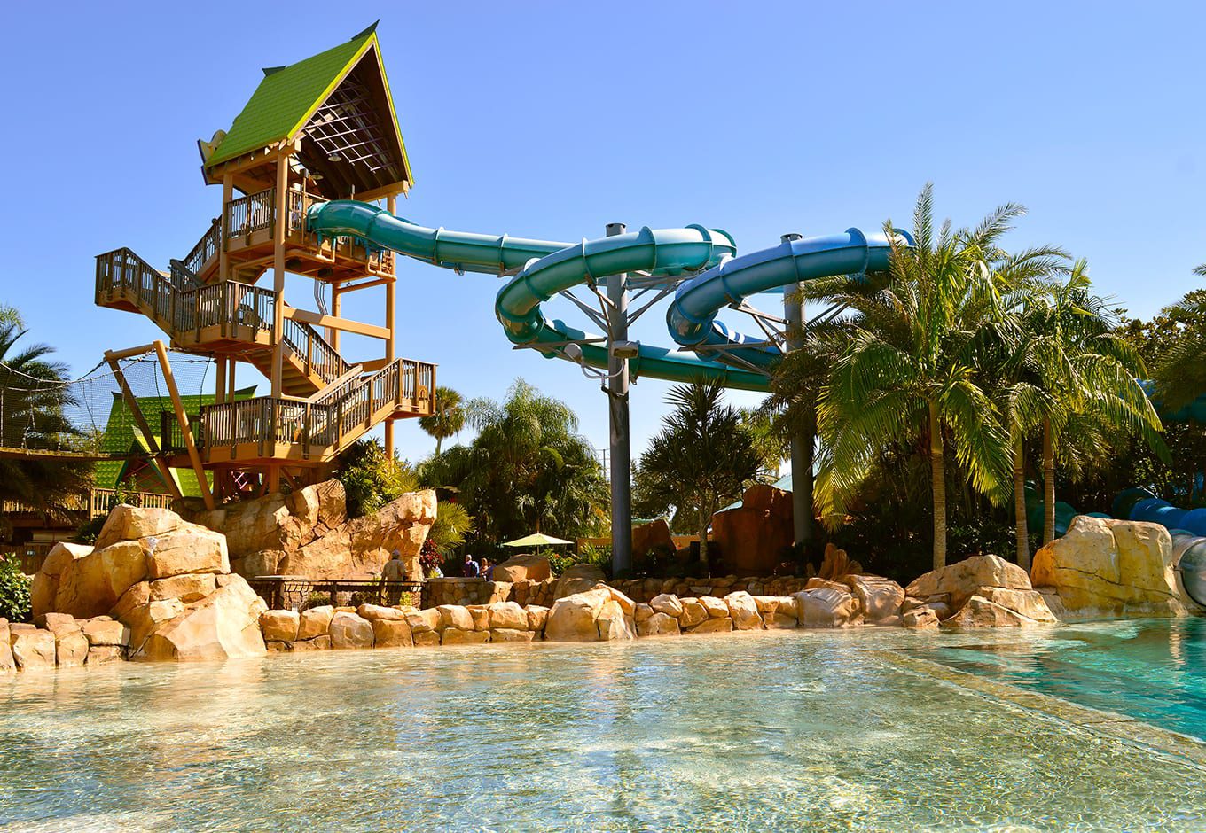 View of ttwo waterslides and a pristine pool surrounded by palm trees at the Aquatica Water Park, Orlando.