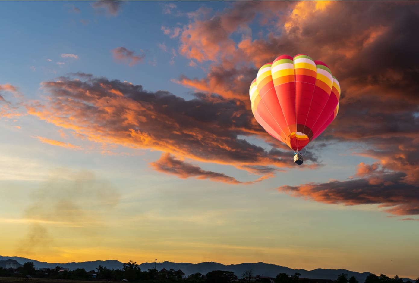 An orange and yellow hot air flying at sunset time. balloon