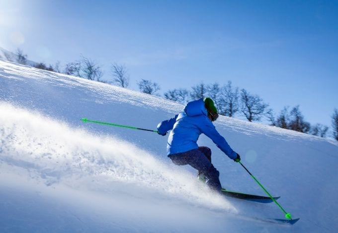 A person downhill skiing in a mountain.