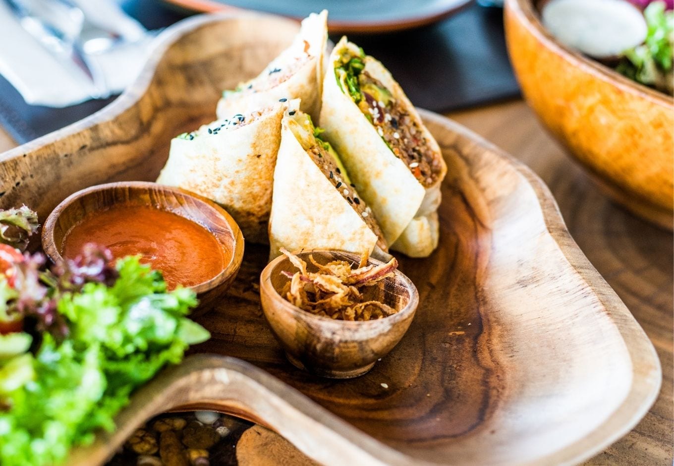 Vegan burritos over a wooden plate.