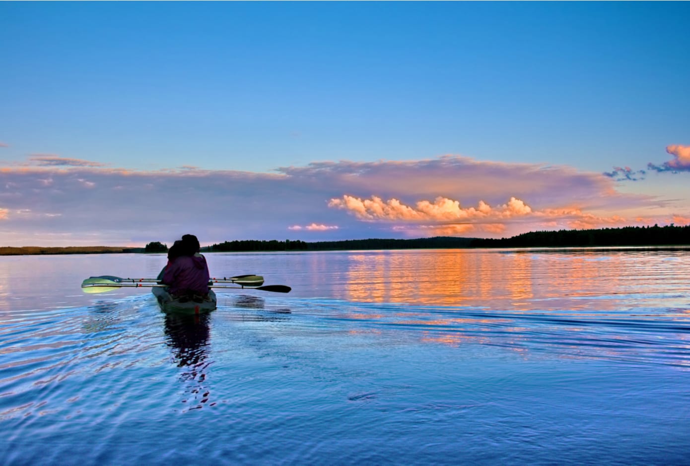 Two people kayaking at sunset.