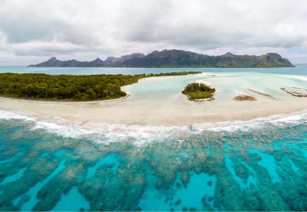 Aerial view of Raivavae island with sandy beaches, coral reef and green islets motu in azure turquoise blue lagoon