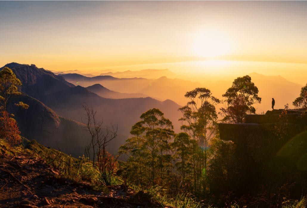Silhouette of a woman watching the sunrise at Dolphin's nose in Kodaikanal, India.