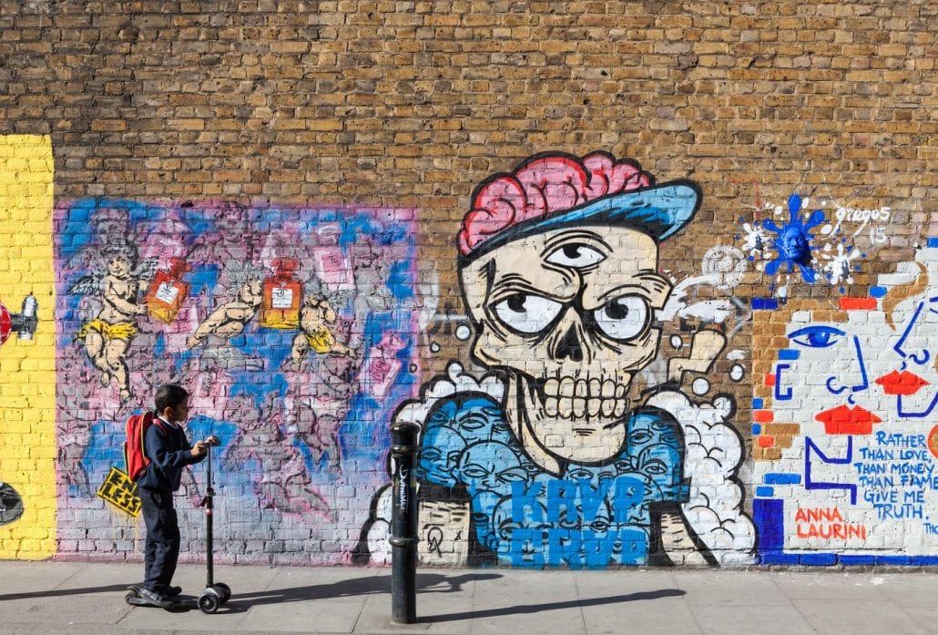 A kid in front of a street art mural in the trendy neighborhood of Shoreditch, London.