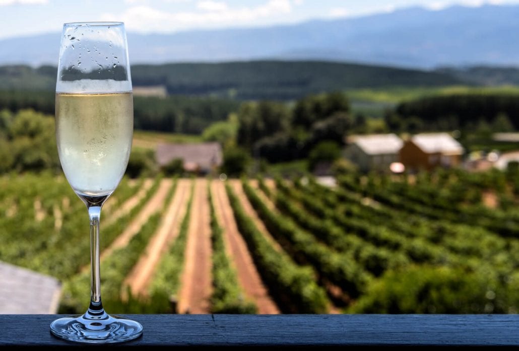 A glass of sparkling wine with a beautiful winery on the backdrop.