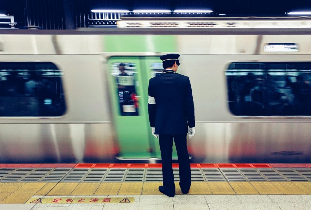 A metro employee standing in front of a passing train inside the Shibuya Station, in Tokyo, Japan.