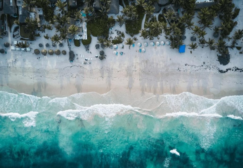 Aerial view of Tulum beach with turquoise-blue waters and alabaster white sand in Mexico.