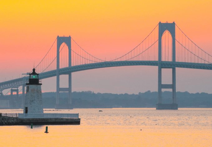 Newport Harbor Lighthouse and the Newport Bridge at sunset, located in the Narragansett Bay.