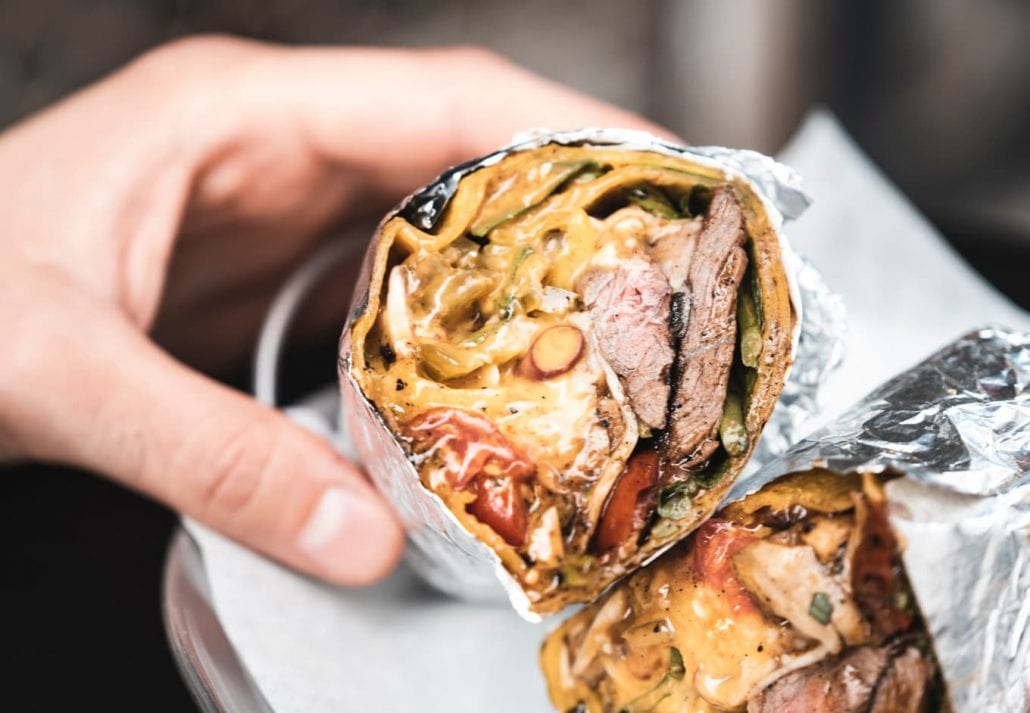 Person holding a giant Mexican burrito cut in half.