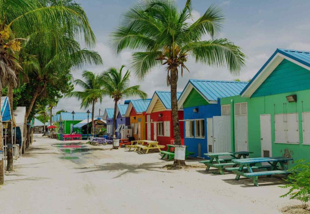 Colorful houses lined up by a white sand beach in Barbados.