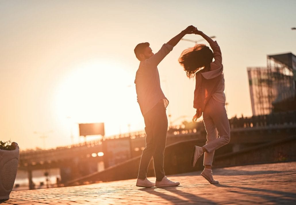Young couple dancing outdoor at sunset.