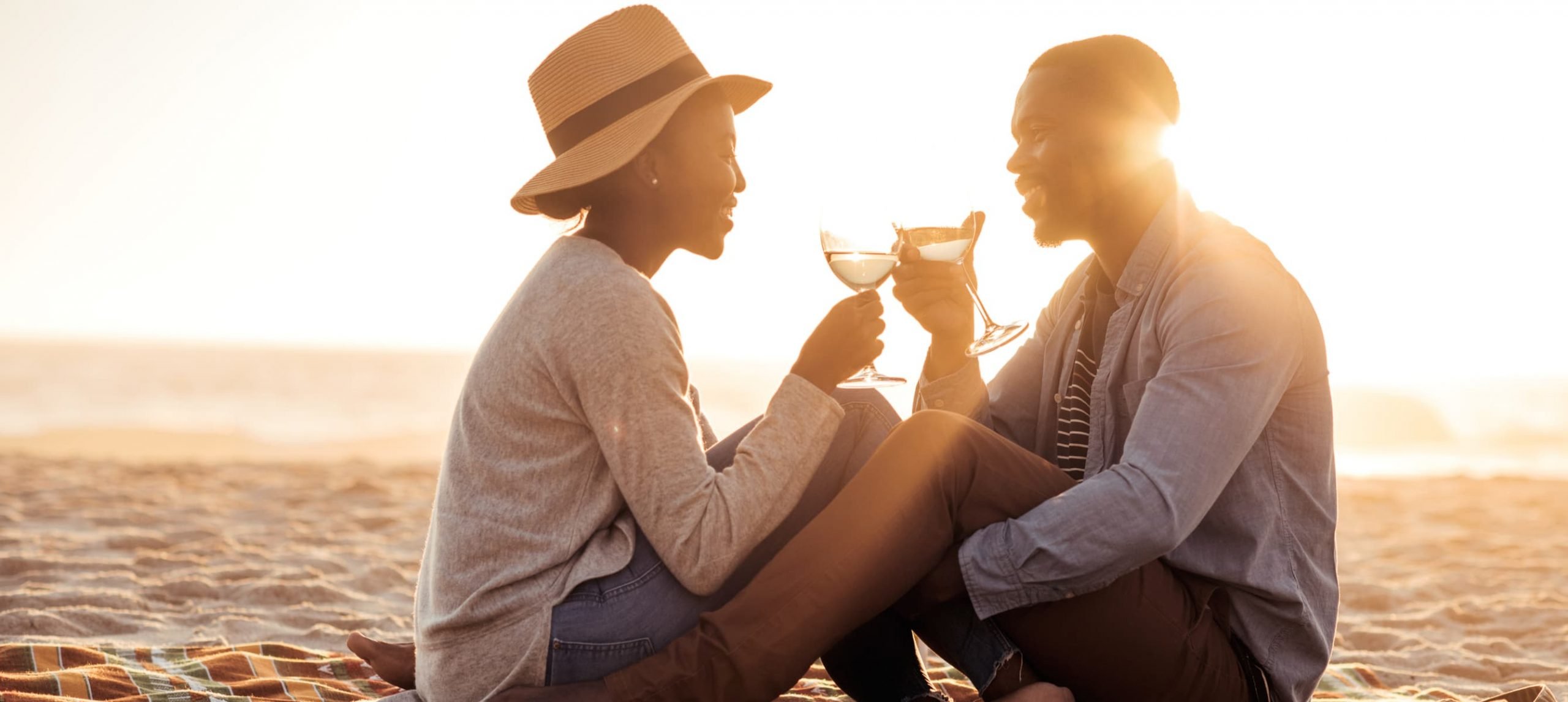 Couple drinking wine at the beach during the sunset.