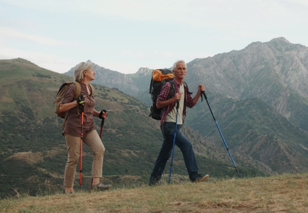 Active senior couple hiking in mountains with backpacks enjoying their adventure.