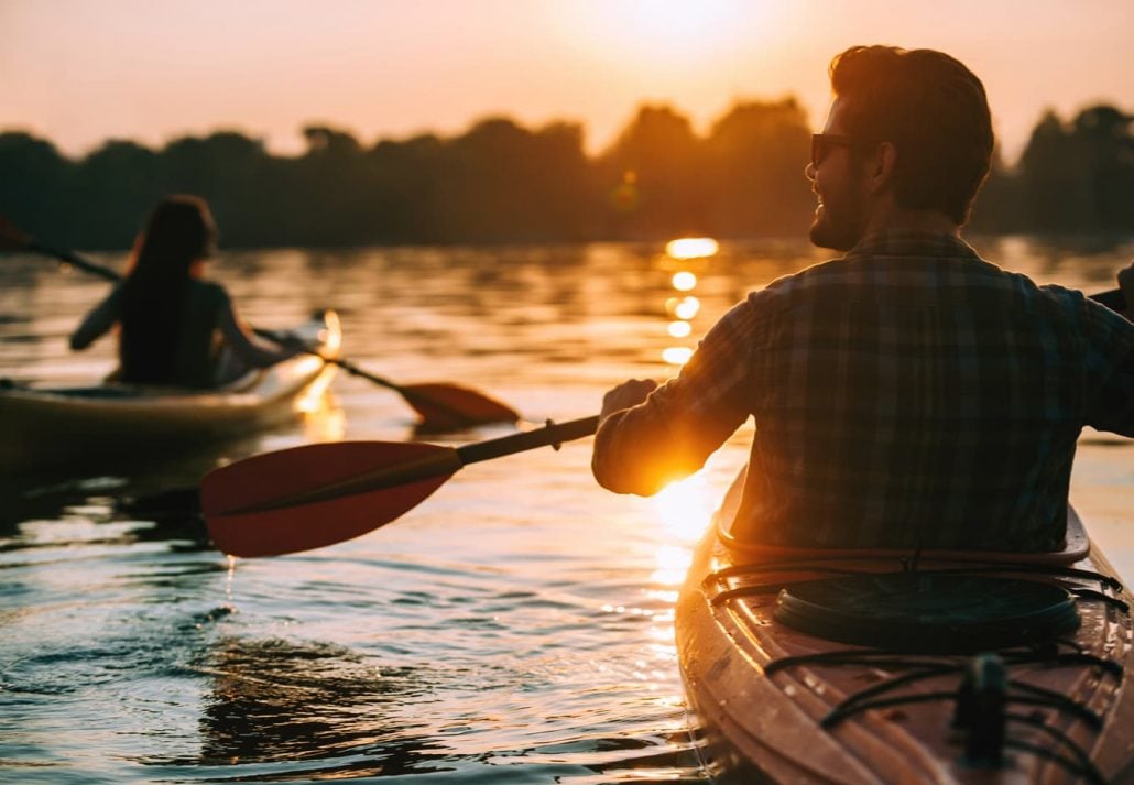 Young couple kayaking at sunset.