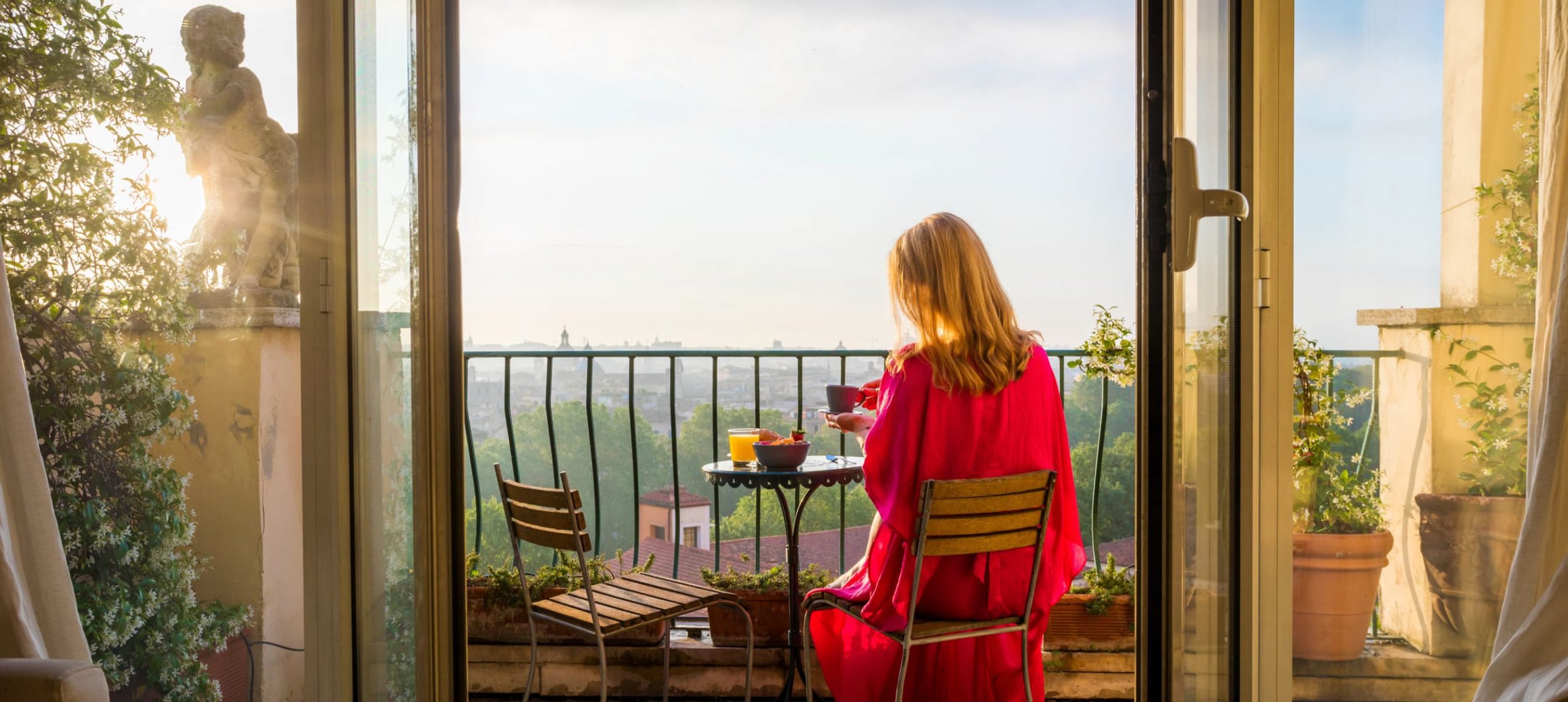 Woman sitting on balcony and overlooking Rome in morning at sunrise