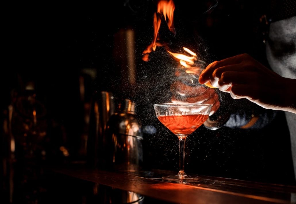 A mixologist creating a drink in a dark bar
