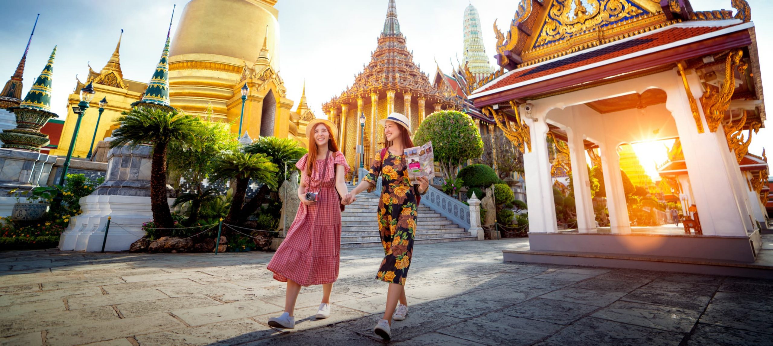 Two young woman walking together in front of a temple in Bangkok, Thailand.
