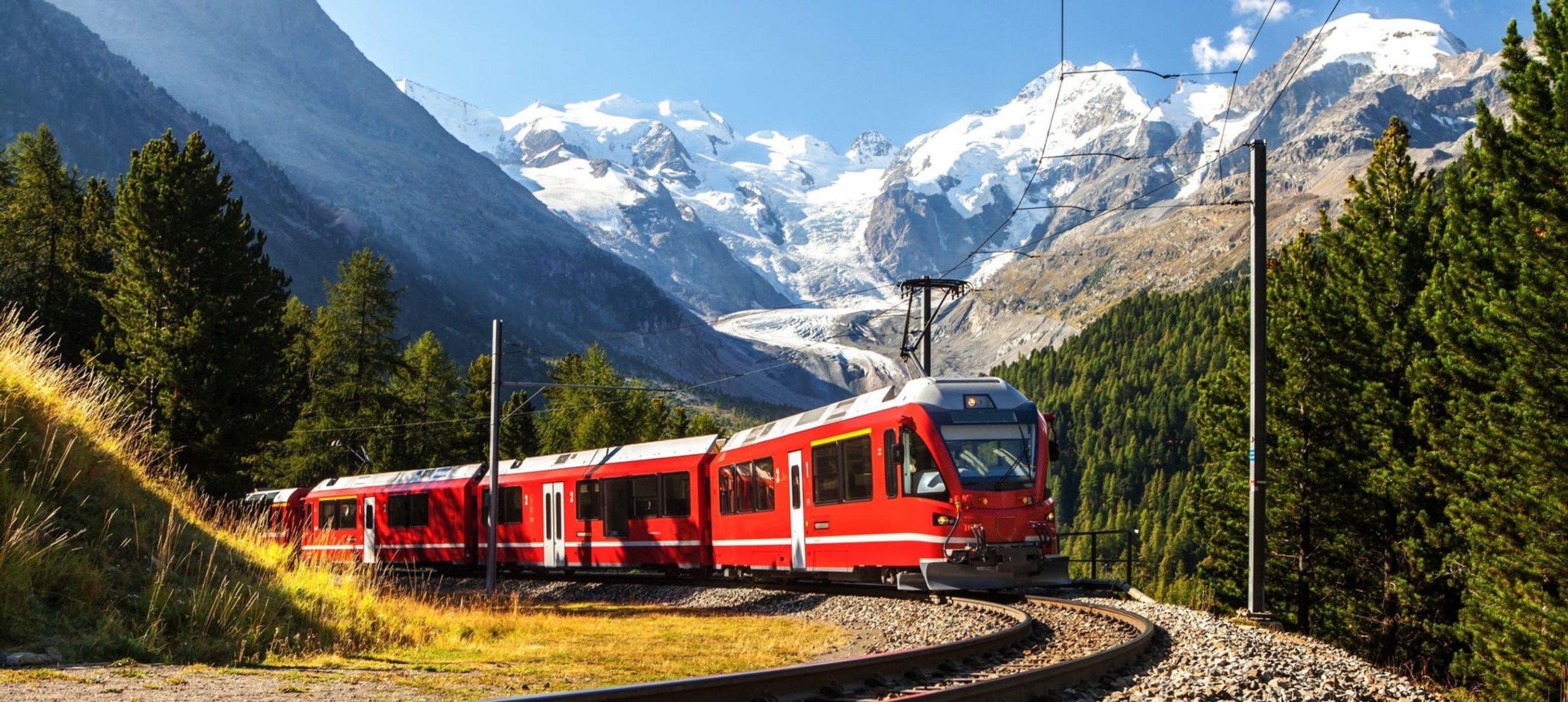 Red train passing through the alps.