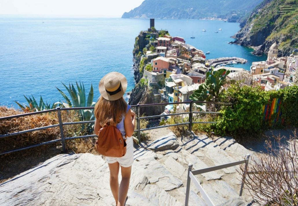 A woman looking at the sea and one of the villages from a hiking trail in Cinque Terre