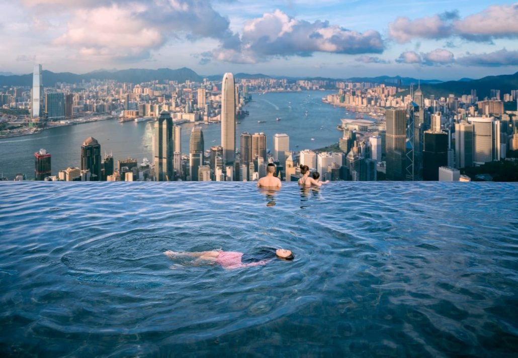 Three peope in an infinite swimming pool in Hong Hong.