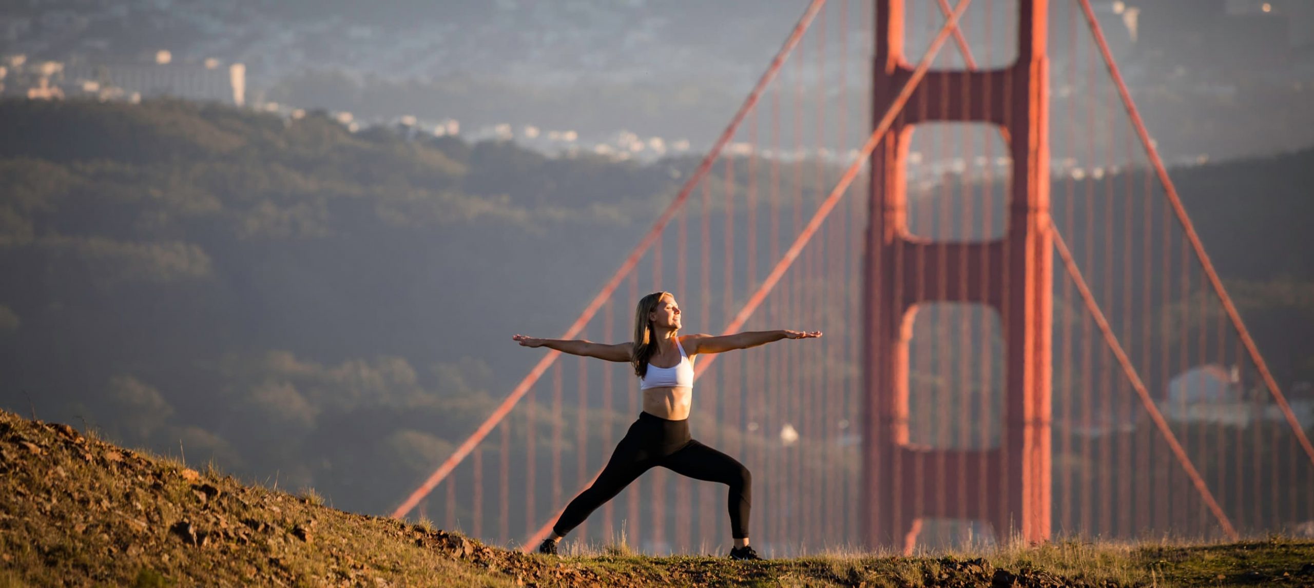 Young woman doing yoga in front of the Golden Gate Bridge, in San Francisco, California.
