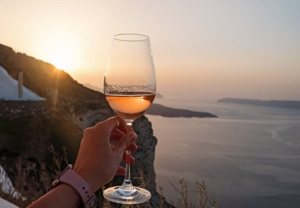 A woman holding a glass of wine with a view of the sea in the background