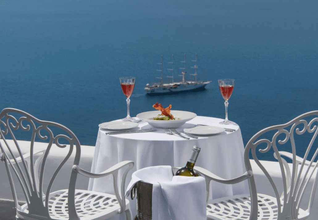 Red wine glasses on a white table overlooking the sea in Santorini