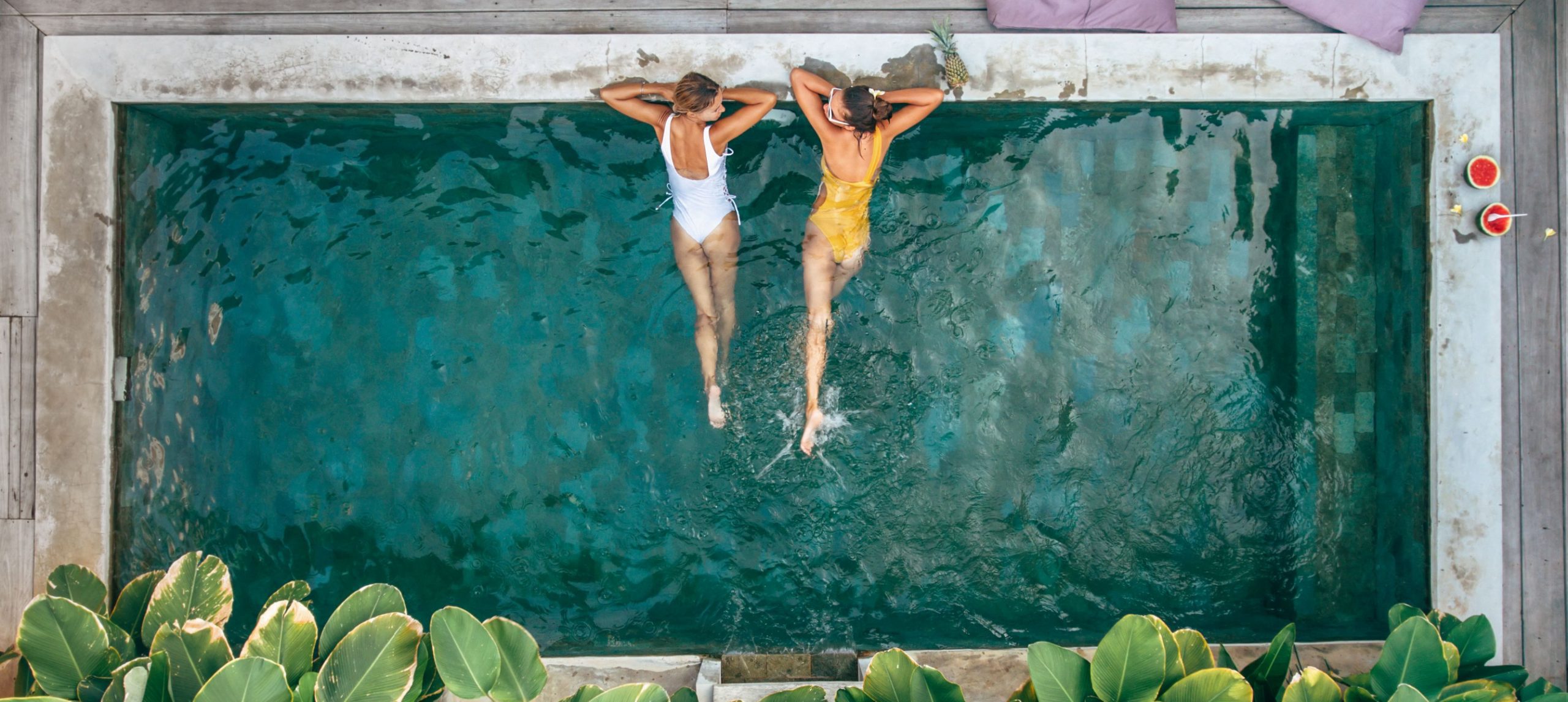 Two young woman talking inside a pool.