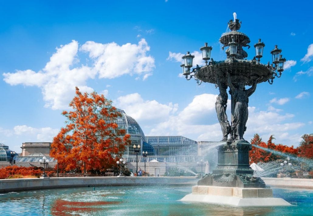 a fountain with trees and a building in the background