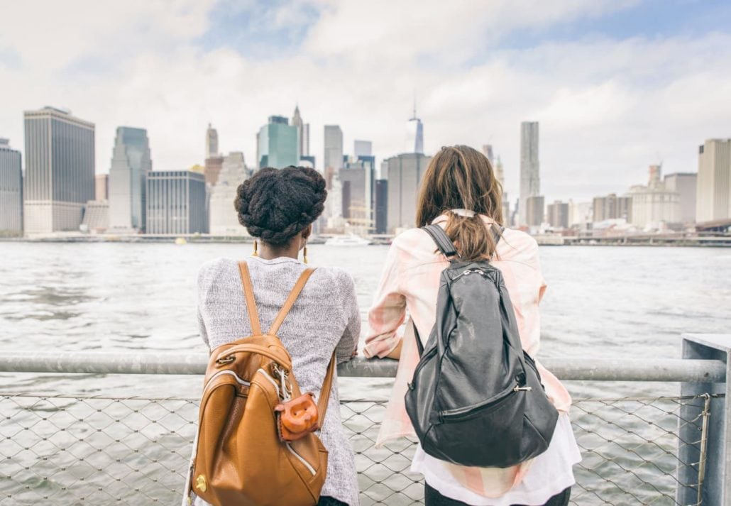 Two young women looking at Manhattan from opposite sides of New York.