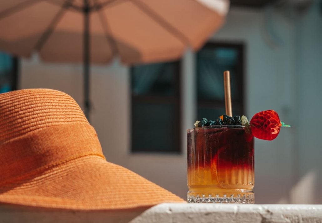 A cocktail on a table next to a hat