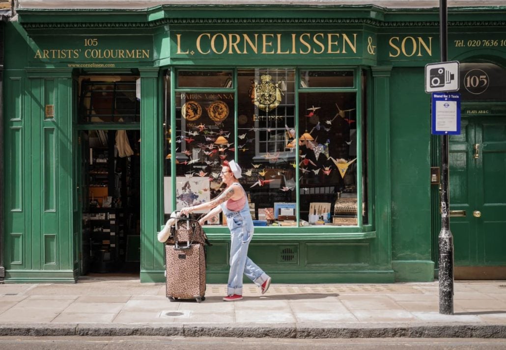 Woman traveler walking in front of a store in Bloomsbury, London, UK.