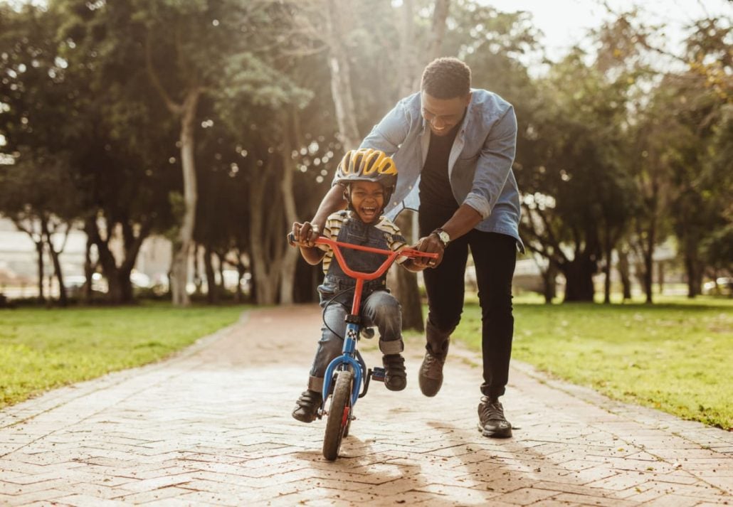 a man assisting a child in riding a bike