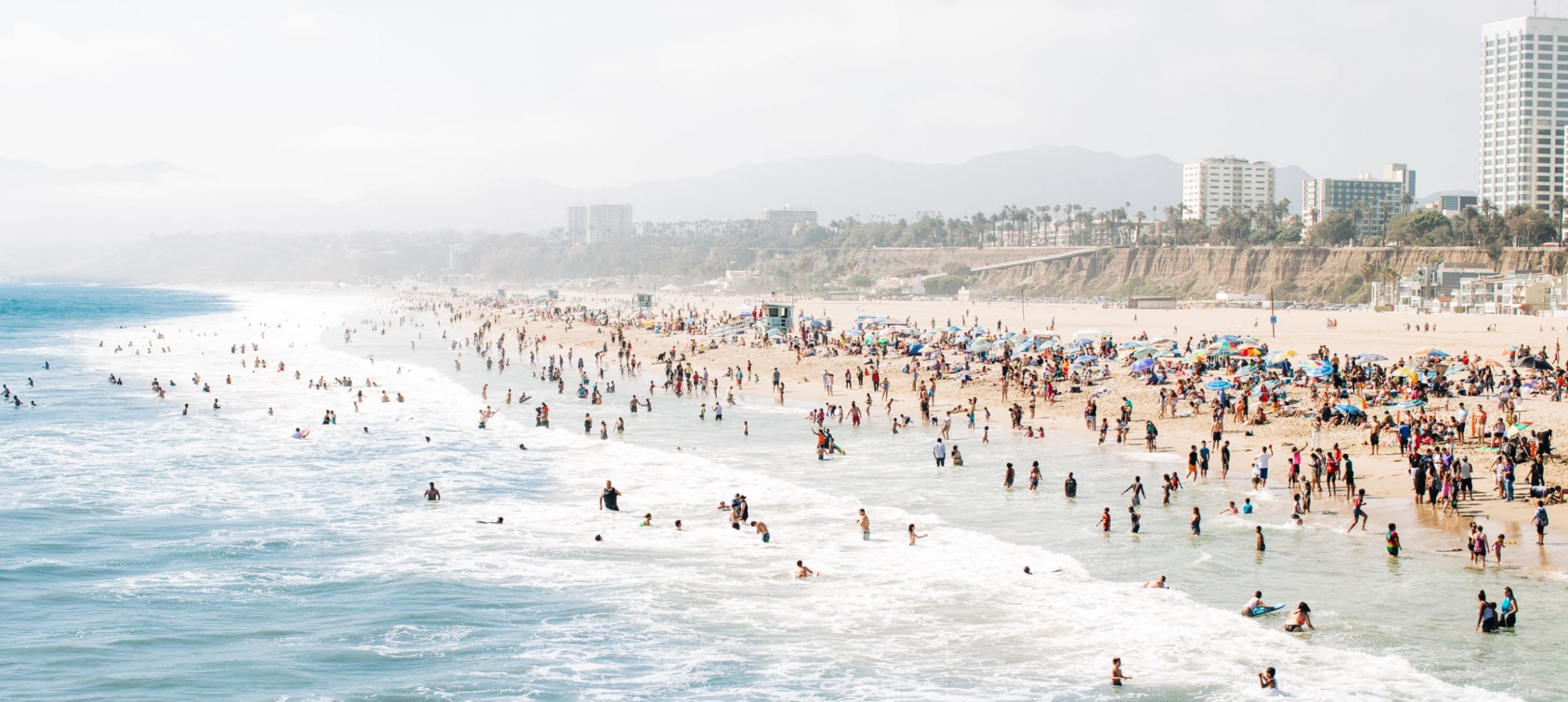 A southern California beach filled with people during the summer.