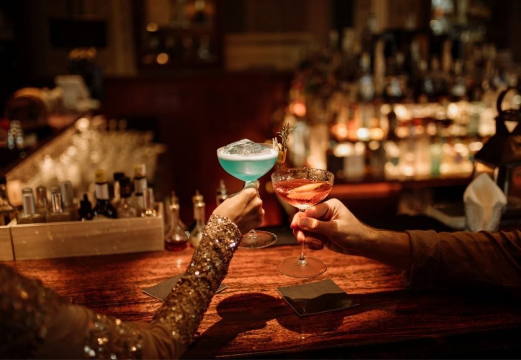 a man and a woman showing glasses filled with cocktails