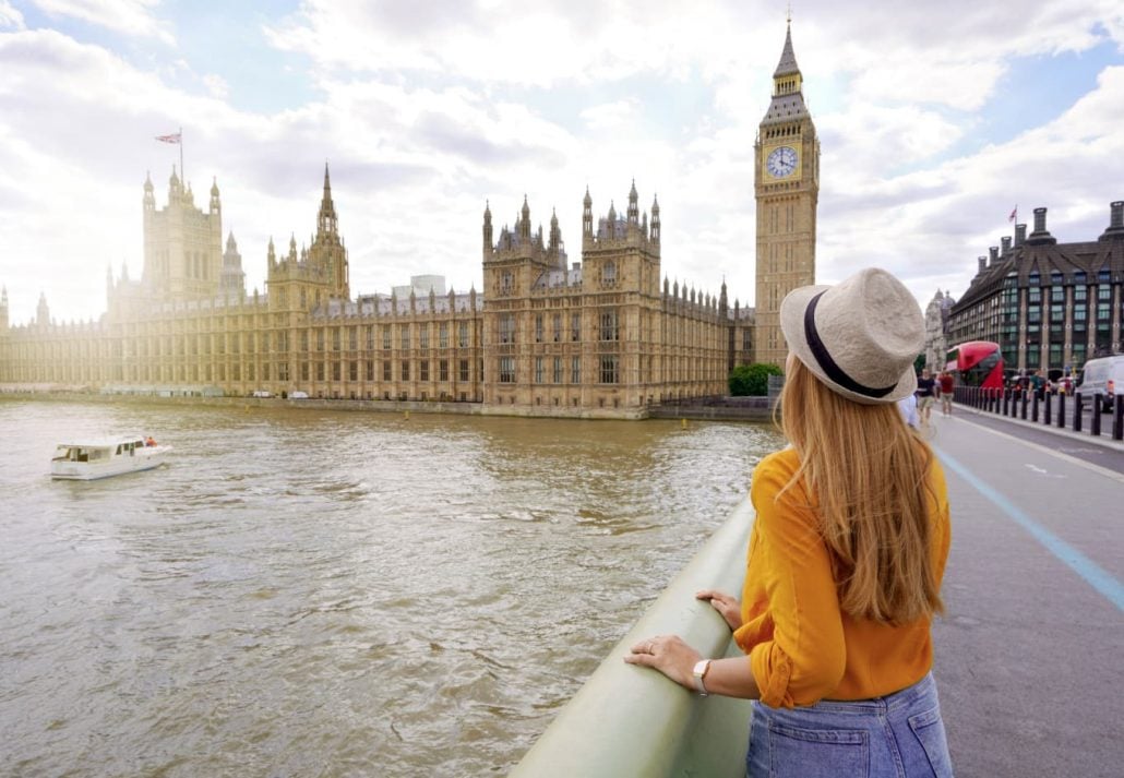 A young woman in London marveling at the Big Ben. 