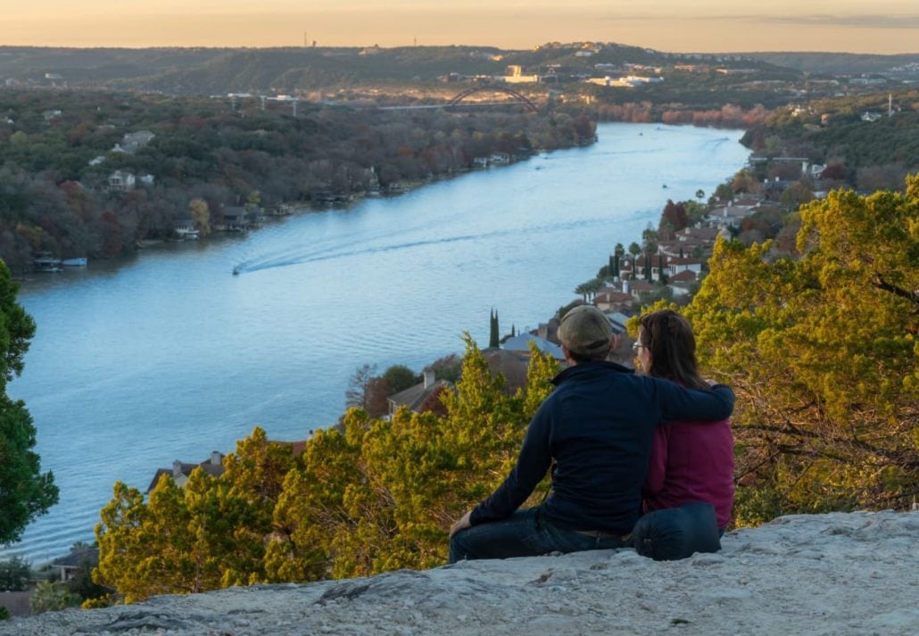 A couple watching the sunset in Austin, Texas at Mount Bonnell overlooking the river.

