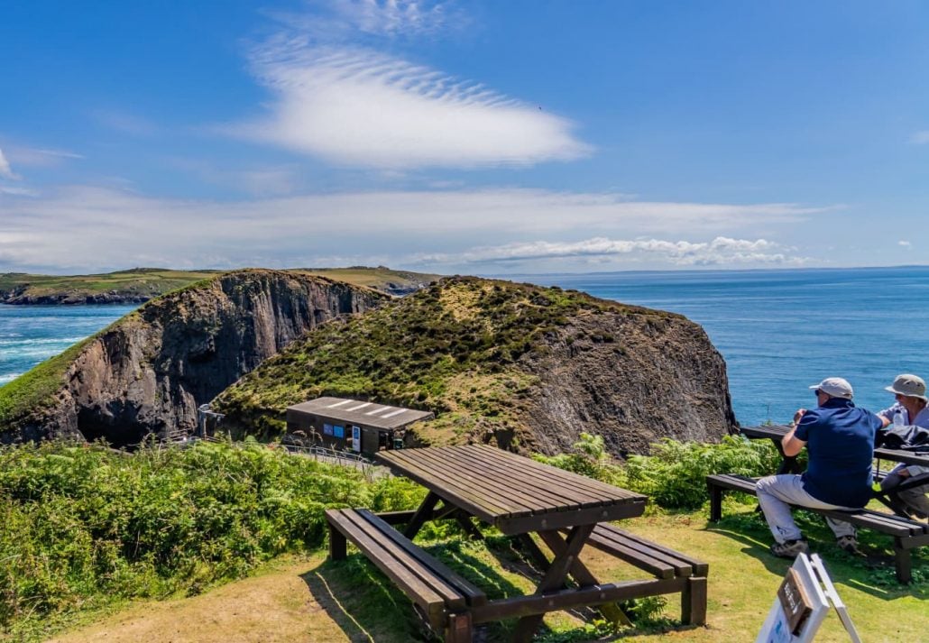 Hikers taking a break on the picnic benches on RSPB Ramsey Island, Pembrokeshire, Wales, UK.