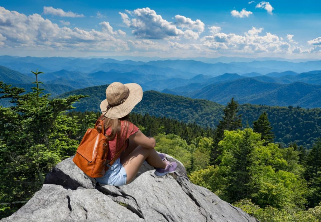  Woman relaxing on top of autumn mountain, over the clouds. Blue Ridge Parkway ,near Asheville, North Carolina, USA.