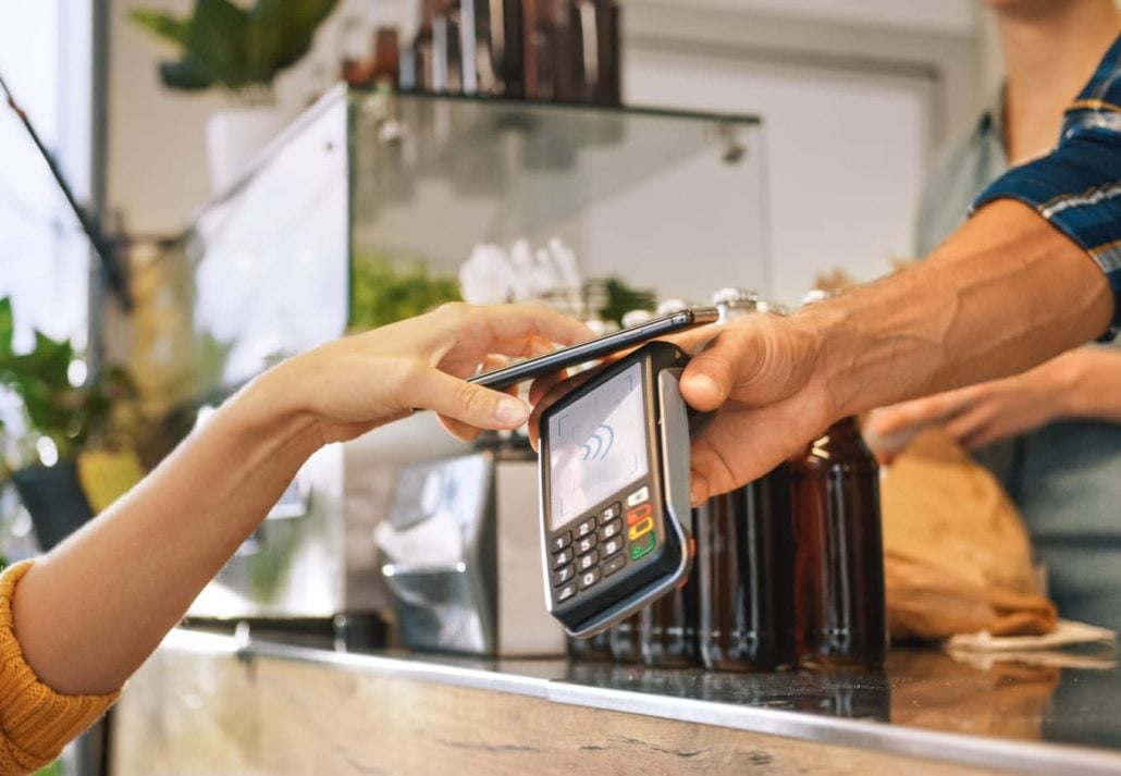 Woman paying a bill at a cafe with her mobile phone.